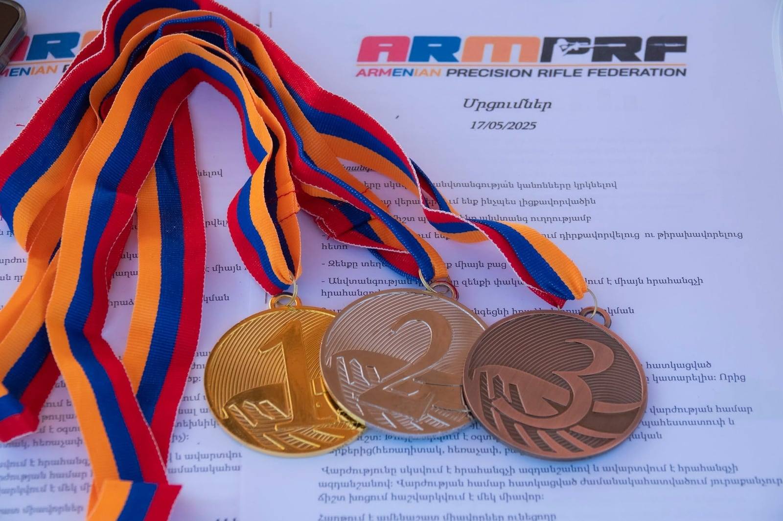 Gold, silver and bronze medals laid on the match rules sheet