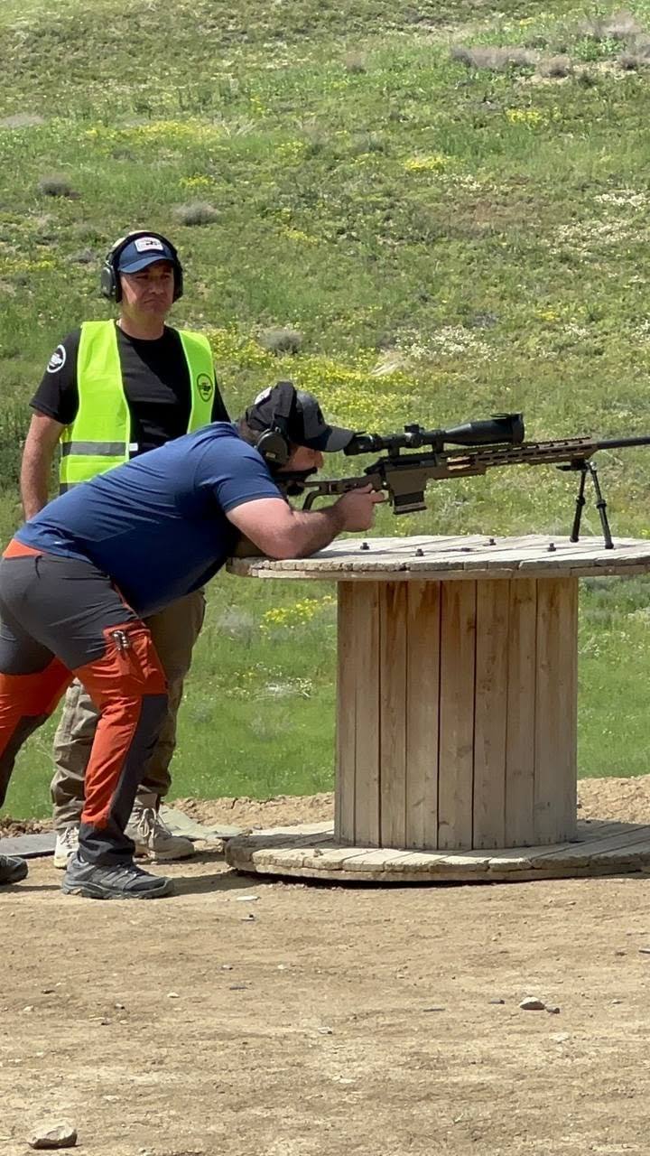 A shooter firing off a cable spool while the range officer watches