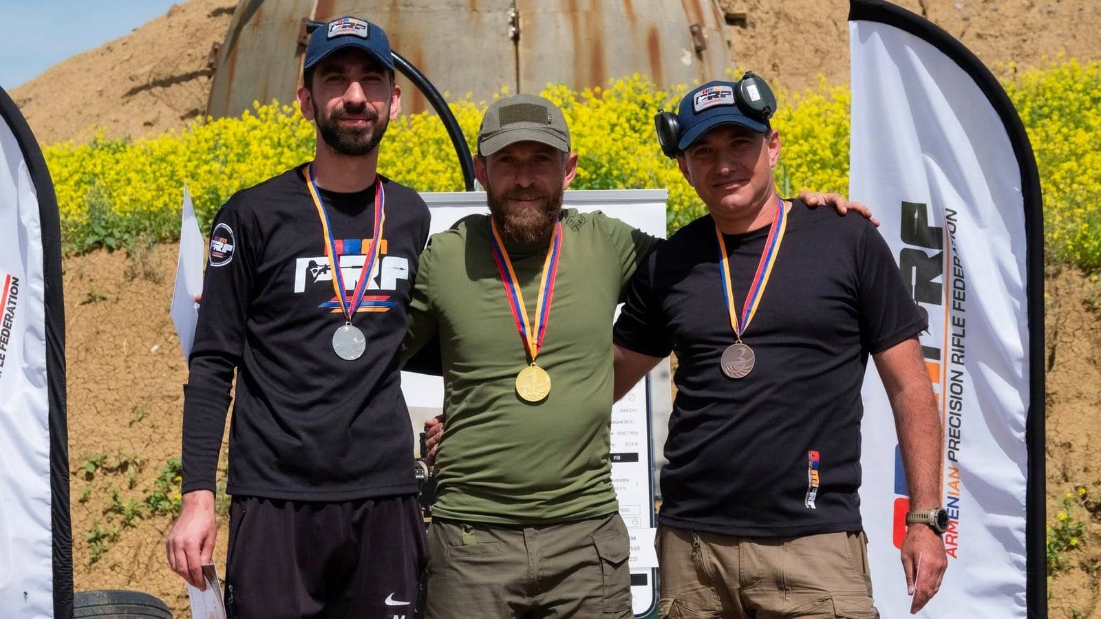 The top three with their medals in front of the ARMPRF banners