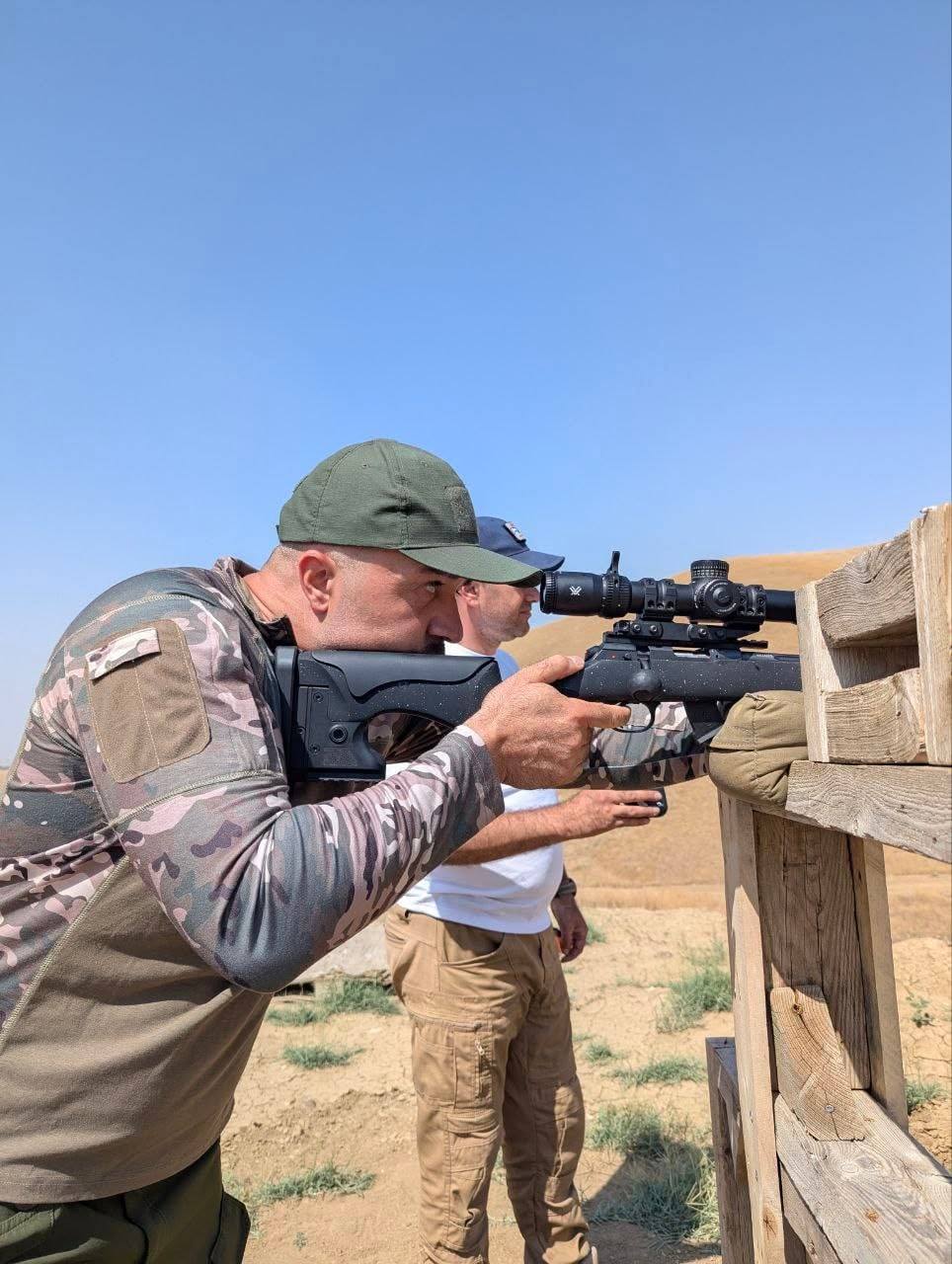 A shooter firing a .22LR rifle off a wooden barricade