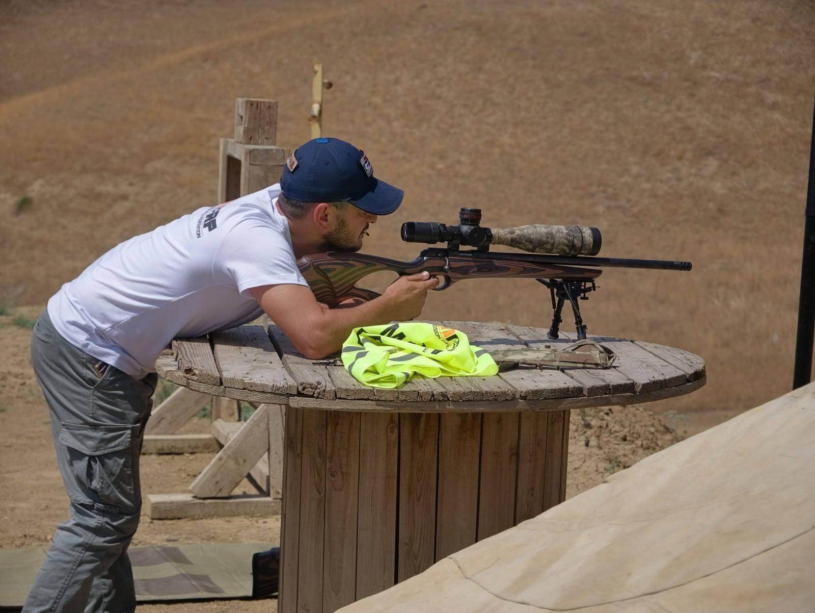 A shooter in an ARMPRF shirt behind a .22LR rifle on a rest