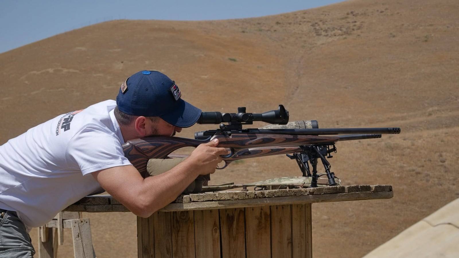 A shooter firing a .22LR rifle off a wooden table on a bipod