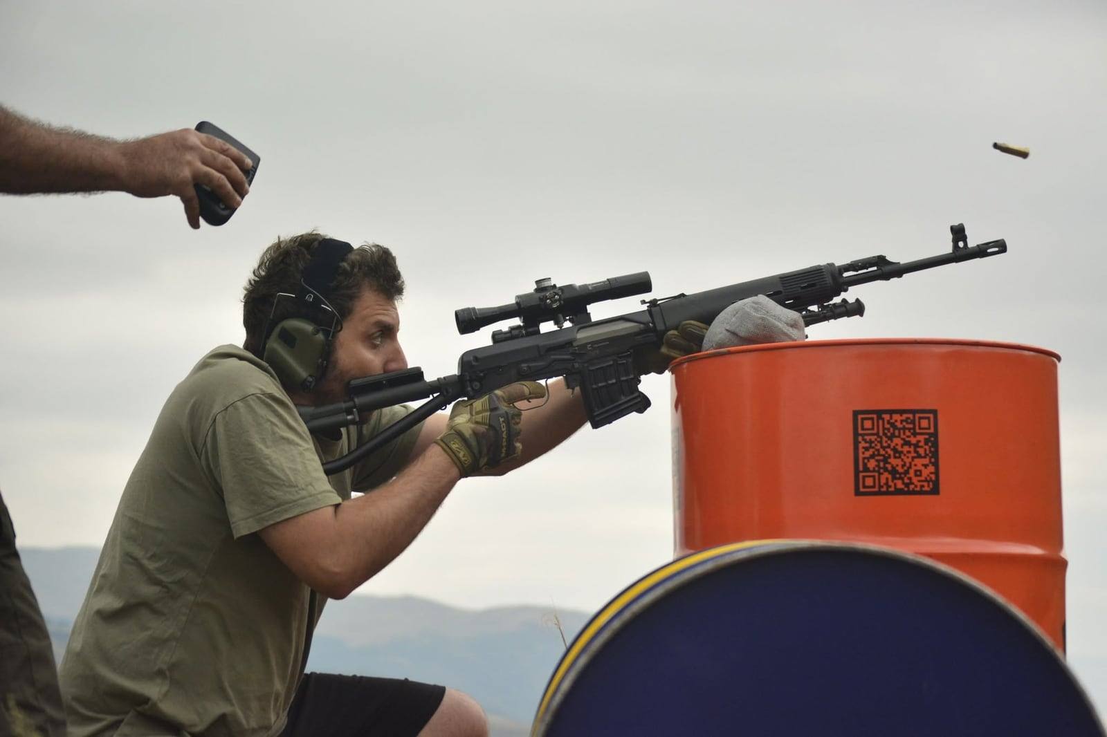 A shooter kneeling behind an SVD, the ejected case still in the air