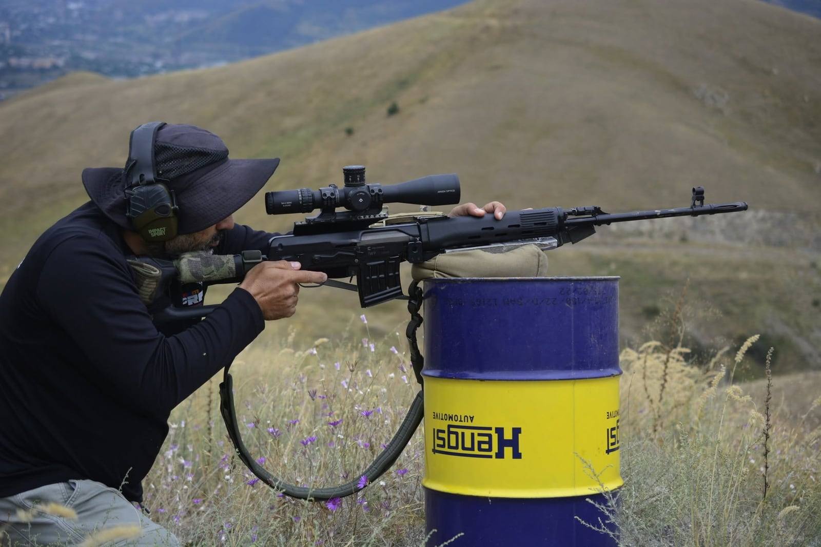 A shooter in a wide-brimmed hat firing a Tigr off a barrel rest