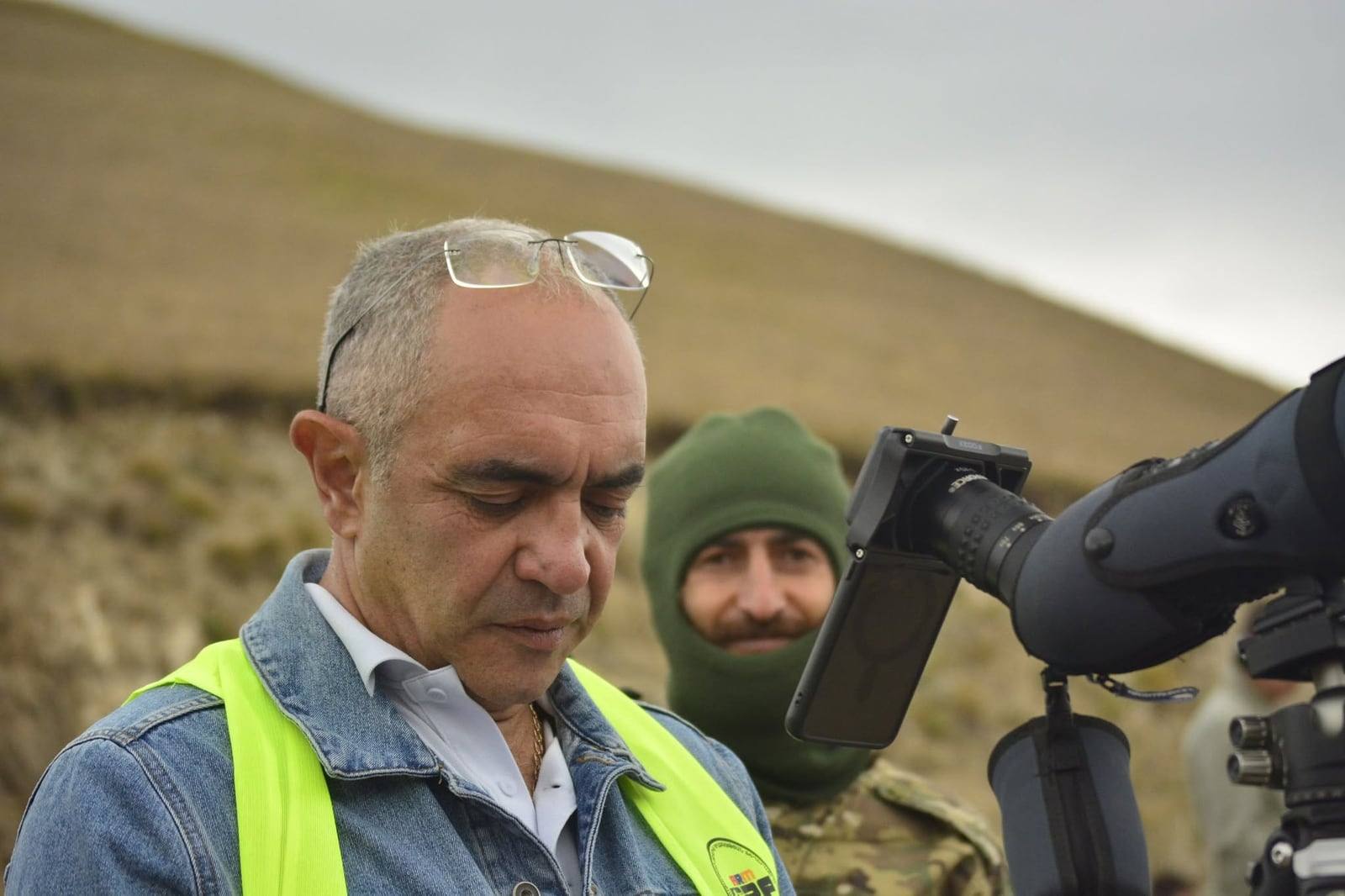 An official behind a spotting scope, recording impacts
