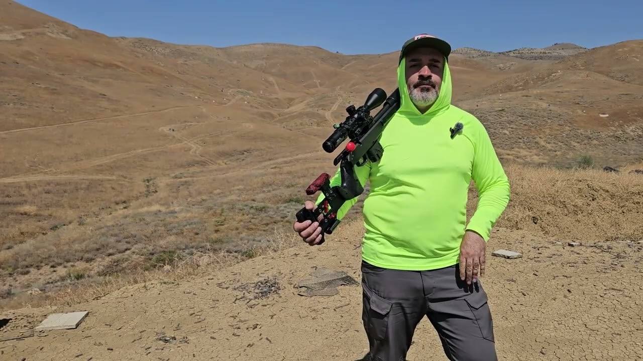 A frame from the video: a shooter in a bright green hoodie on the range, his rifle over his shoulder